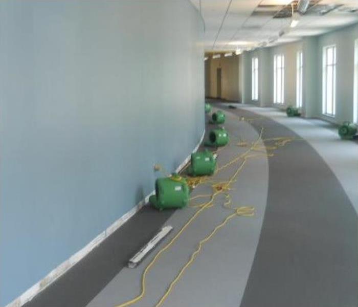 Air movers placed on baseboards, hallway of a commercial building