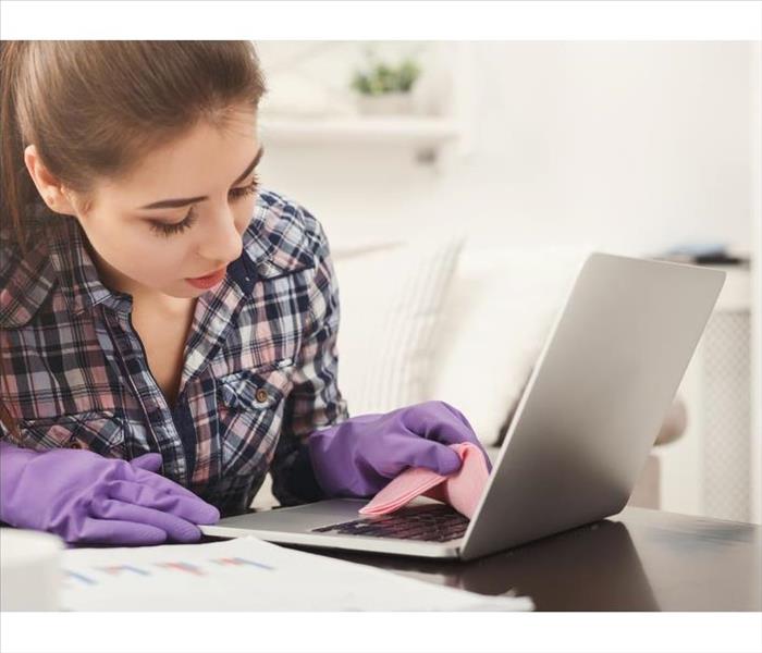 Girl wearing purple gloves cleaning a computer